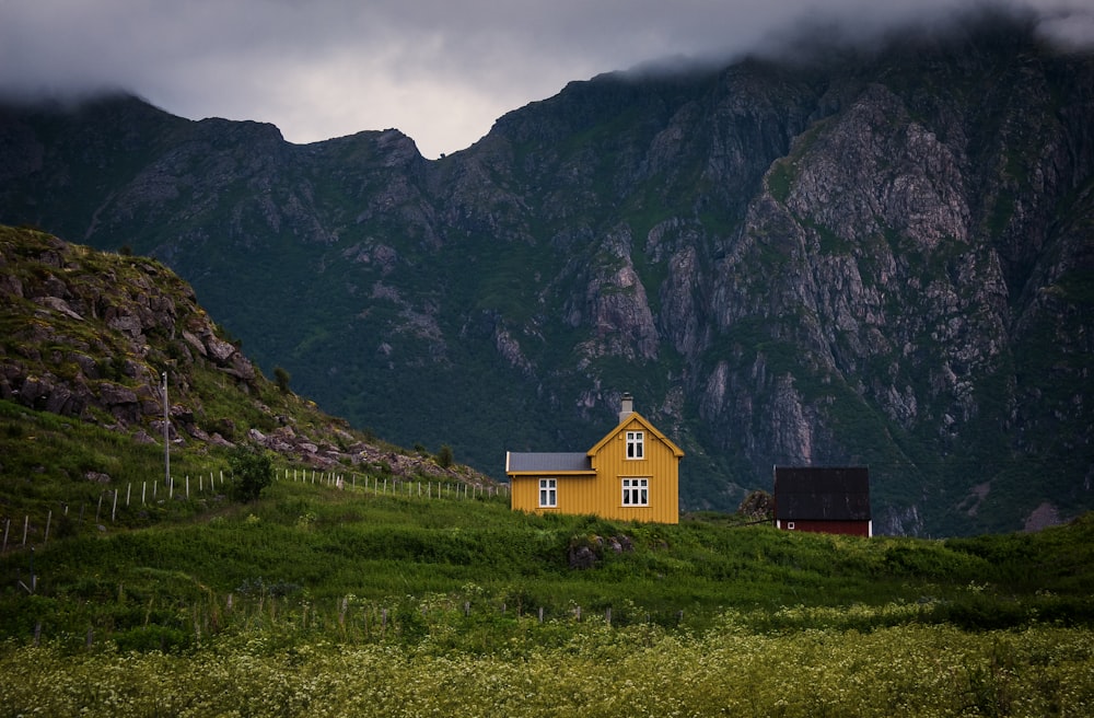 yellow wooden house near mountain during cloudy day