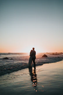 Candid photo of a couple embracing under the golden glow of sunset at the beach.