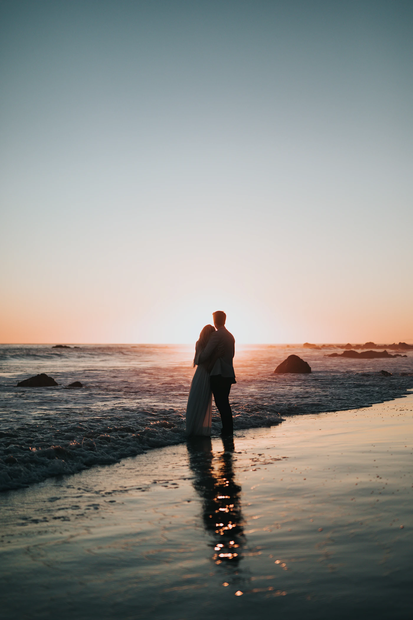 Budget honeymoon destinations in the USA — A couple walks along an uncrowded stretch of coastline at golden hour.