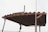 A rustic metal roof structure with a weathered sign displaying the text 'BN0670'. The roof is supported by metal poles and has a corrugated design, evoking a sense of aged industrial utility. A long vertical pole is attached to one side of the structure.