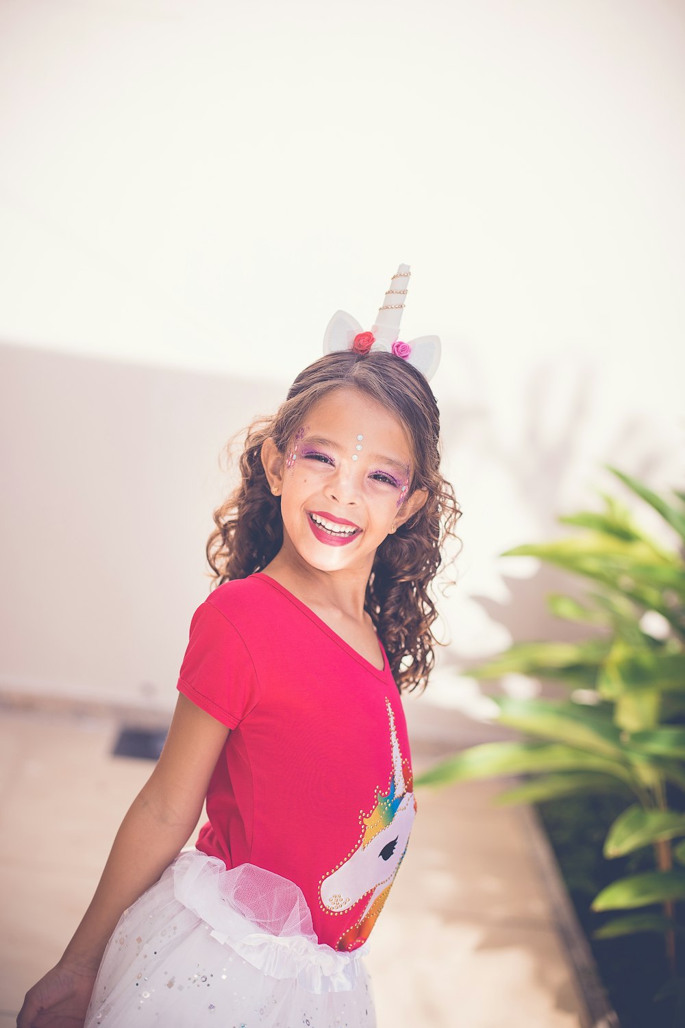 girl smiling near green plant