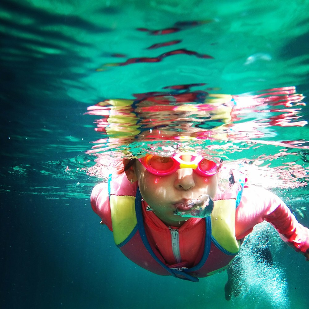 person in pink zip-up jacket swimming under water