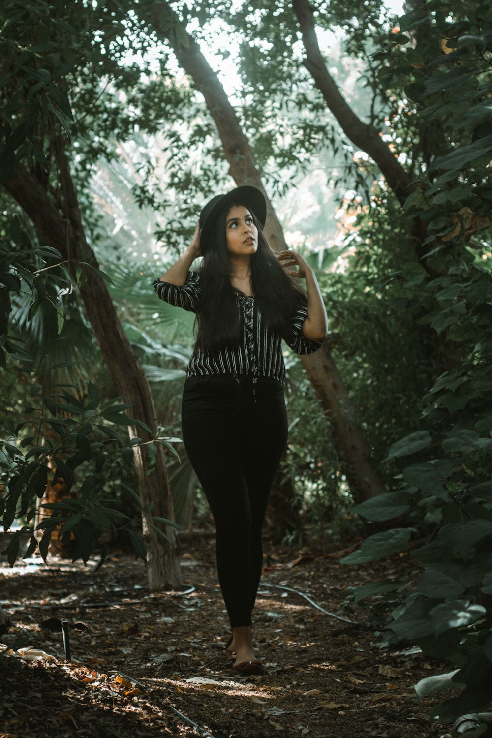 woman walking while looking on her left side and holding her hat during daytime