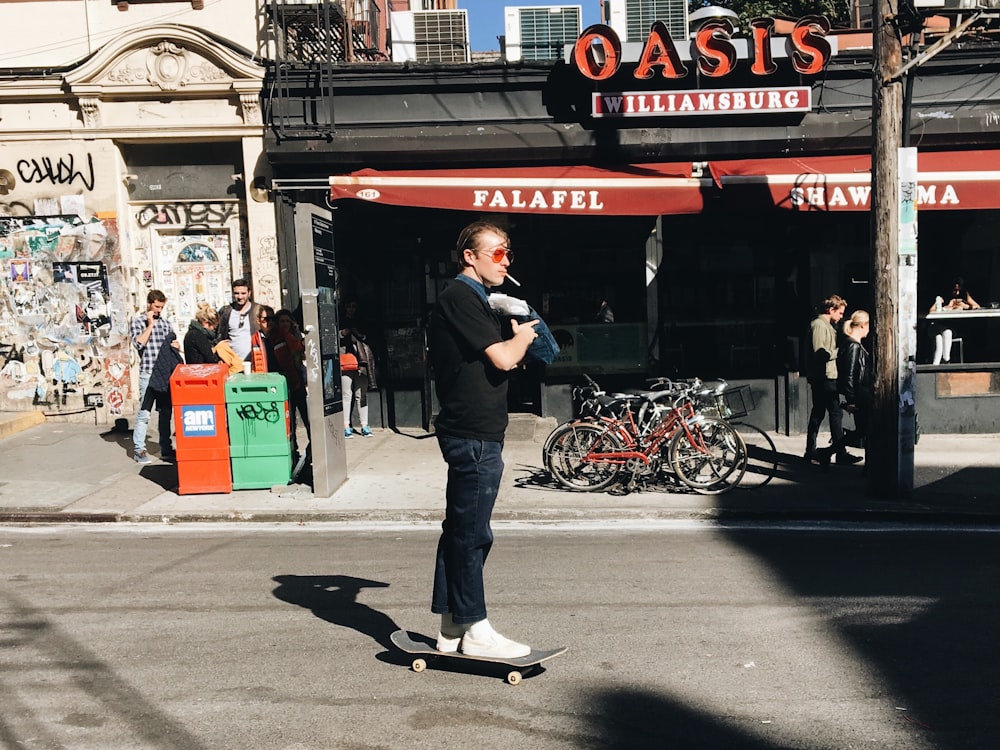 Homem andando de skate perto do prédio cinza e vermelho durante o dia