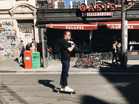 man riding skate near gray and red building during daytime in Brooklyn United States