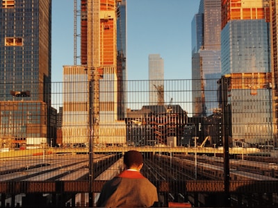 person facing gate and high-rise buildings