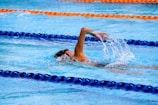 Young swimmer mid-stroke during a freestyle event in a bright blue pool.