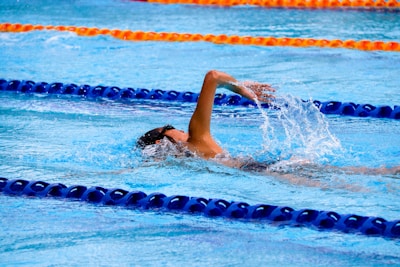 Young swimmer mid-stroke during a freestyle event in a bright blue pool.