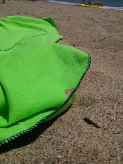 A vibrant beach towel spread out on golden sand under a sunny sky.