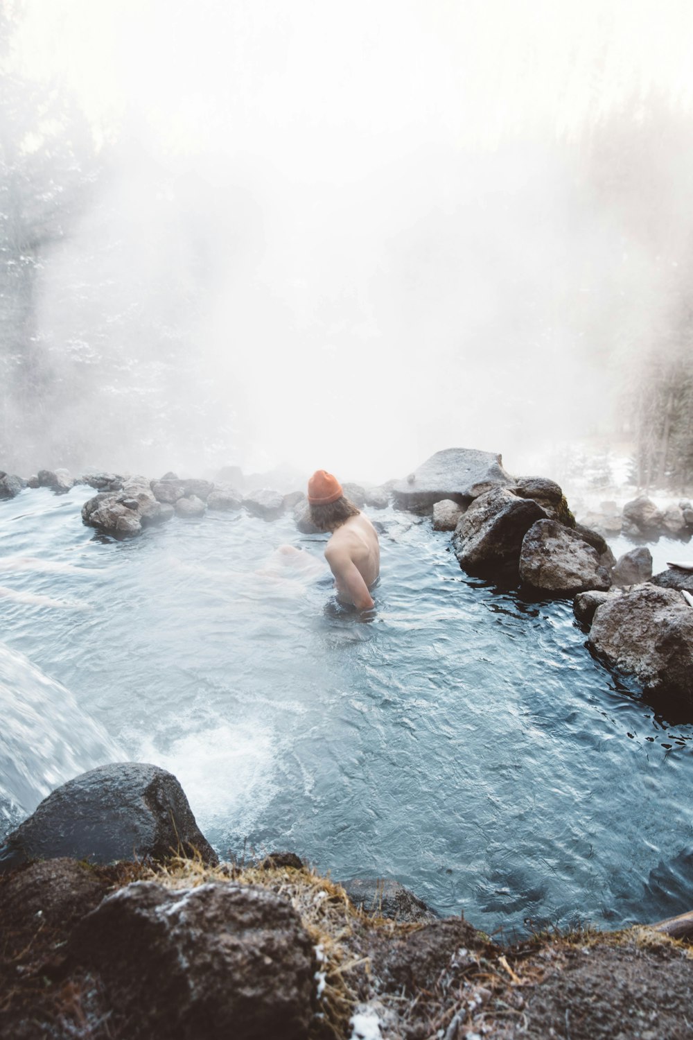 man sitting in water with fog during daytime