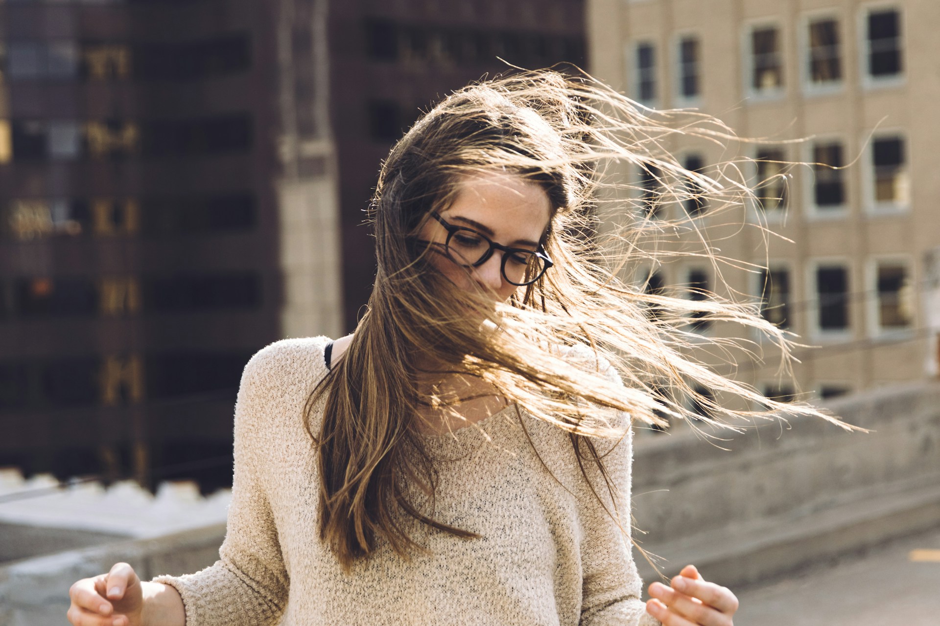 woman standing near building with hair being blown by wind