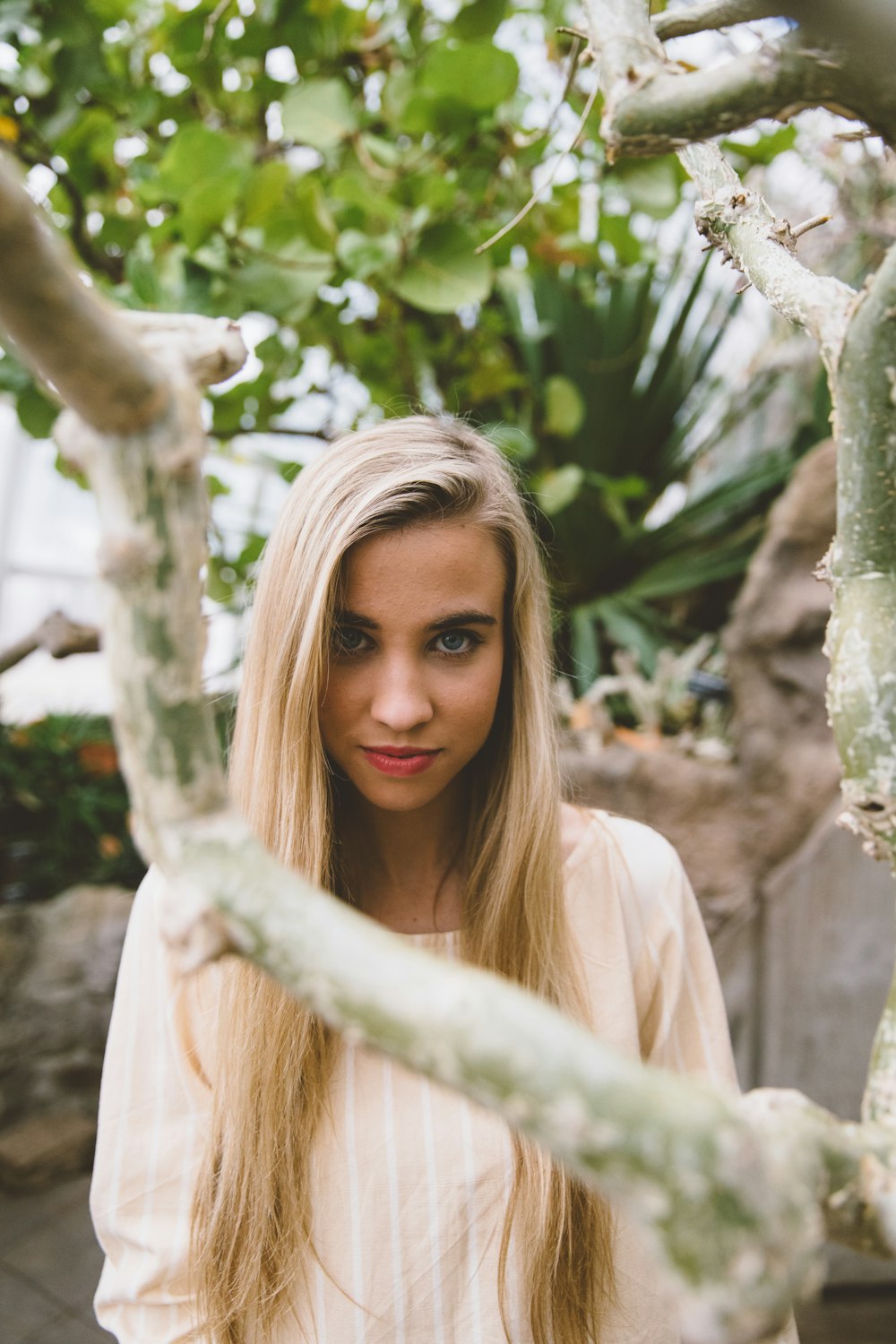 woman wearing peach-colored scoop-neck top standing near green leafed tree