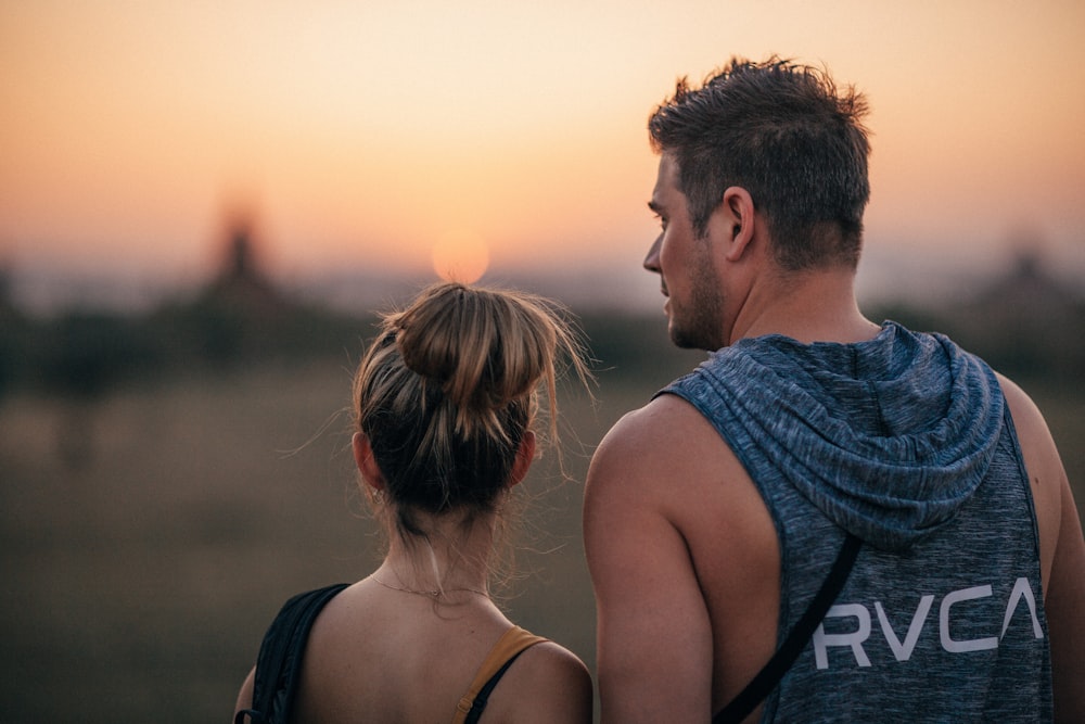 selective focus photography of man standing beside woman while watching sunset