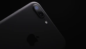 Close-up of a sleek black iPhone with a glowing yellow background highlighting its design