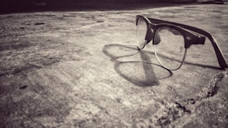 An artistic shot of eyeglasses casting shadows on a textured fabric.
