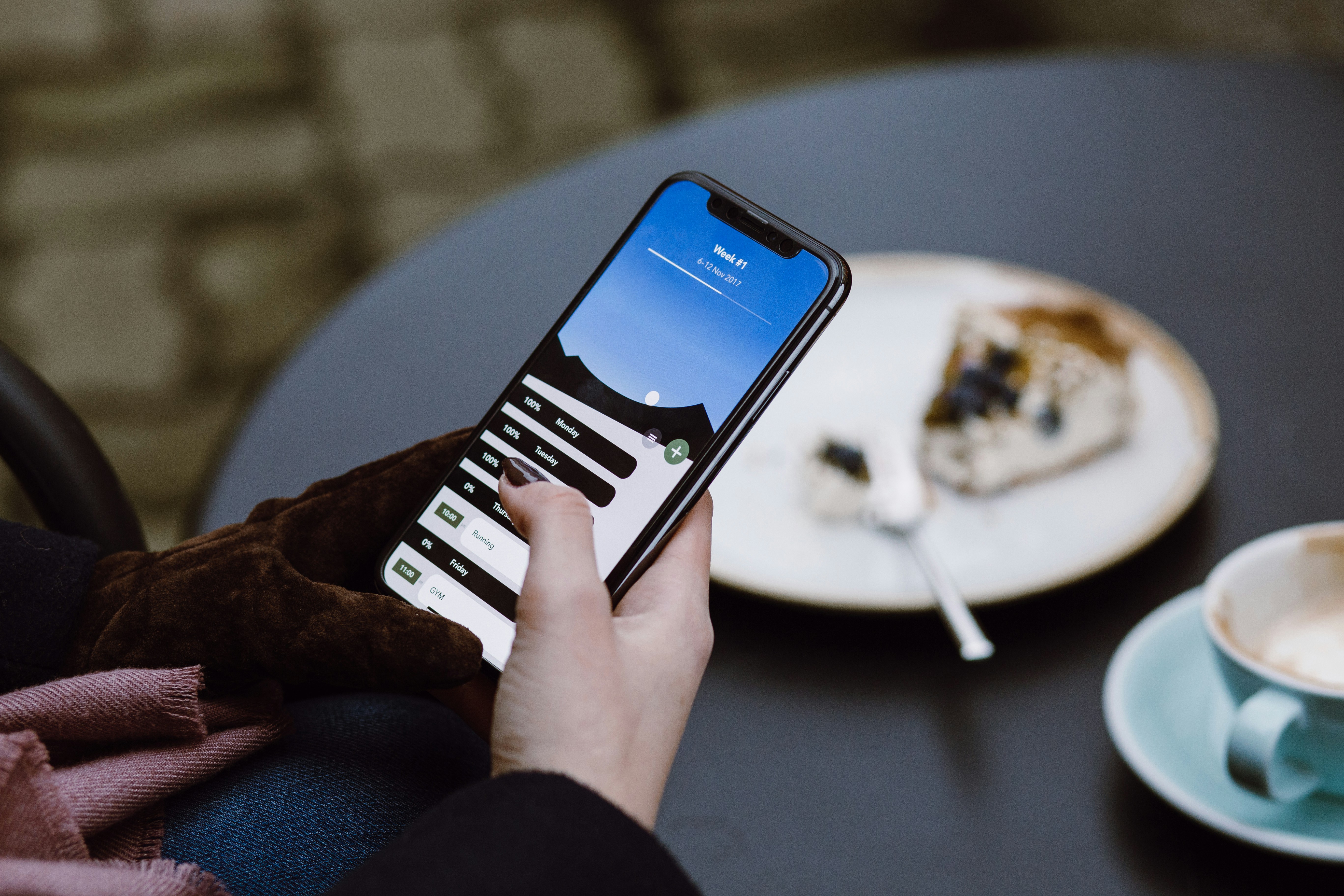 A person using a smartphone to plan weekly meals in a bright kitchen with fresh vegetables on the counter.