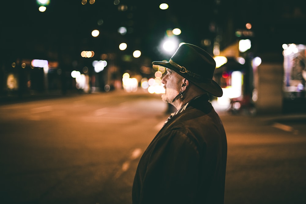 man standing on roadside at night time