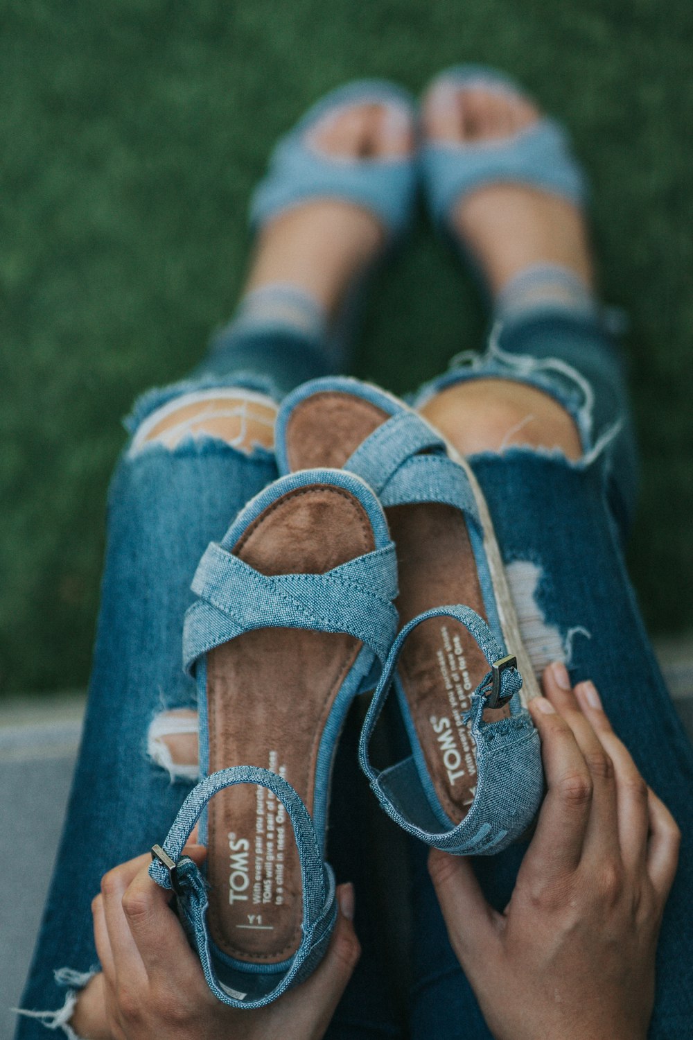 woman holding a pair of blue sandals during daytime