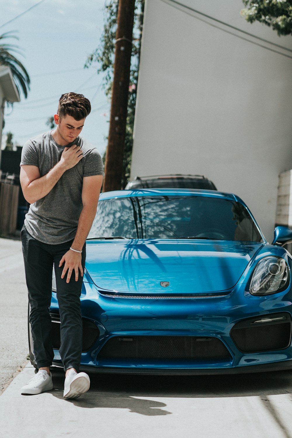 man standing in front of blue car