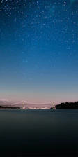 A serene night sky filled with twinkling stars over a quiet bridge.