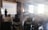 A group of people are seated in a room with exposed brick walls and large windows. Rays of sunlight illuminate the space. A presenter stands in front of a projection screen displaying a slide in Russian, and a flipchart is nearby.