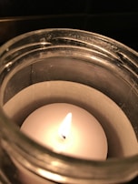 A warm candle flickering softly, surrounded by small bottles of fragrance oils.