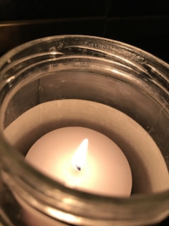 A warm candle flickering softly, surrounded by small bottles of fragrance oils.