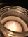 Close-up of a handcrafted stone cast candle vessel glowing softly with a lit candle inside.