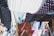Colorful fabrics with various patterns, such as polka dots and floral designs, are hanging on wooden racks and lines. They create a vibrant tapestry of colors and textures, with the sunlight casting dynamic shadows between them.