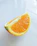 Close-up of a hand holding a vibrant, freshly peeled orange segment with juice glistening.