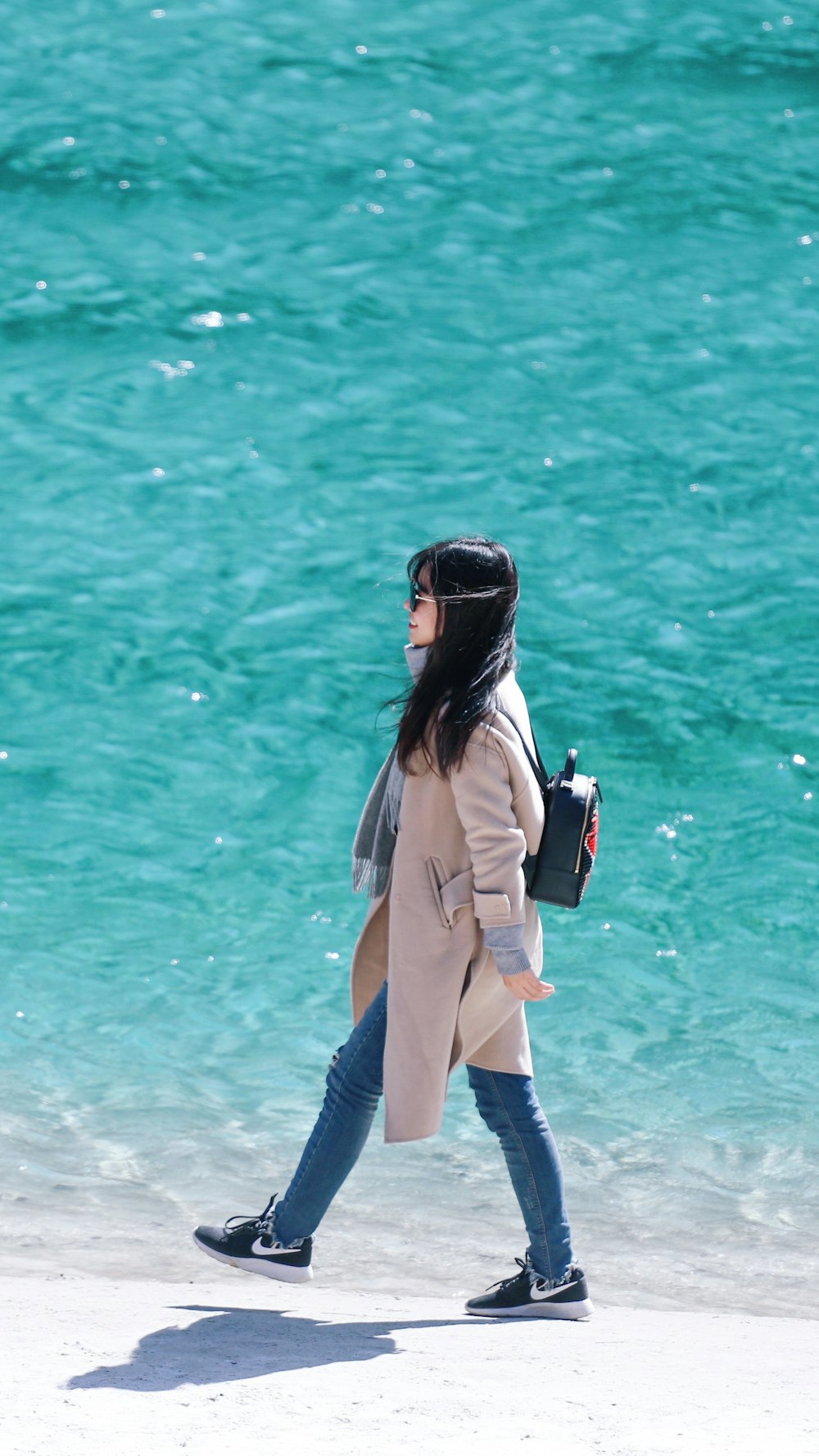 コートを着て海岸を歩く女性