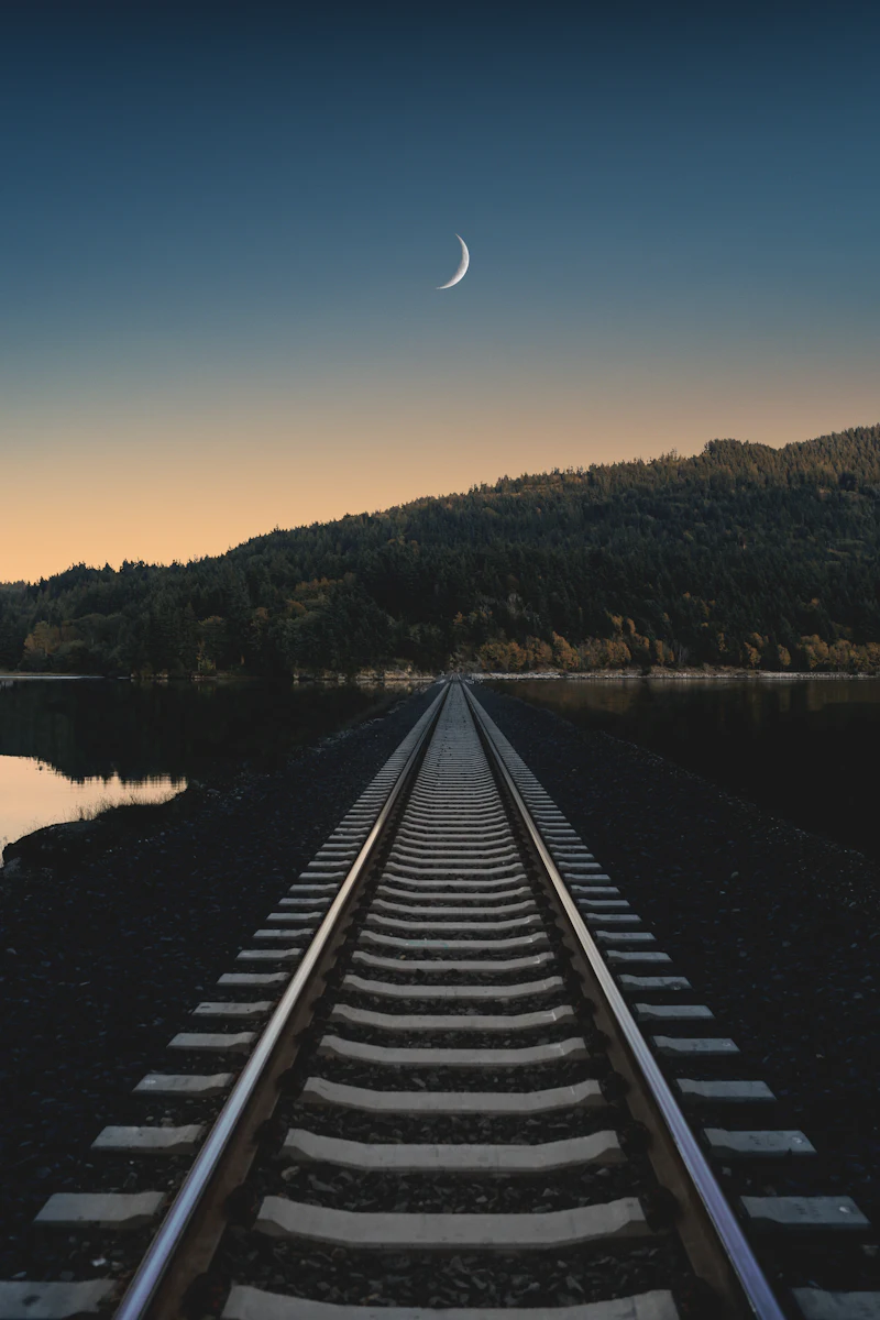 Rail line curving away toward distant mountains under an open sky