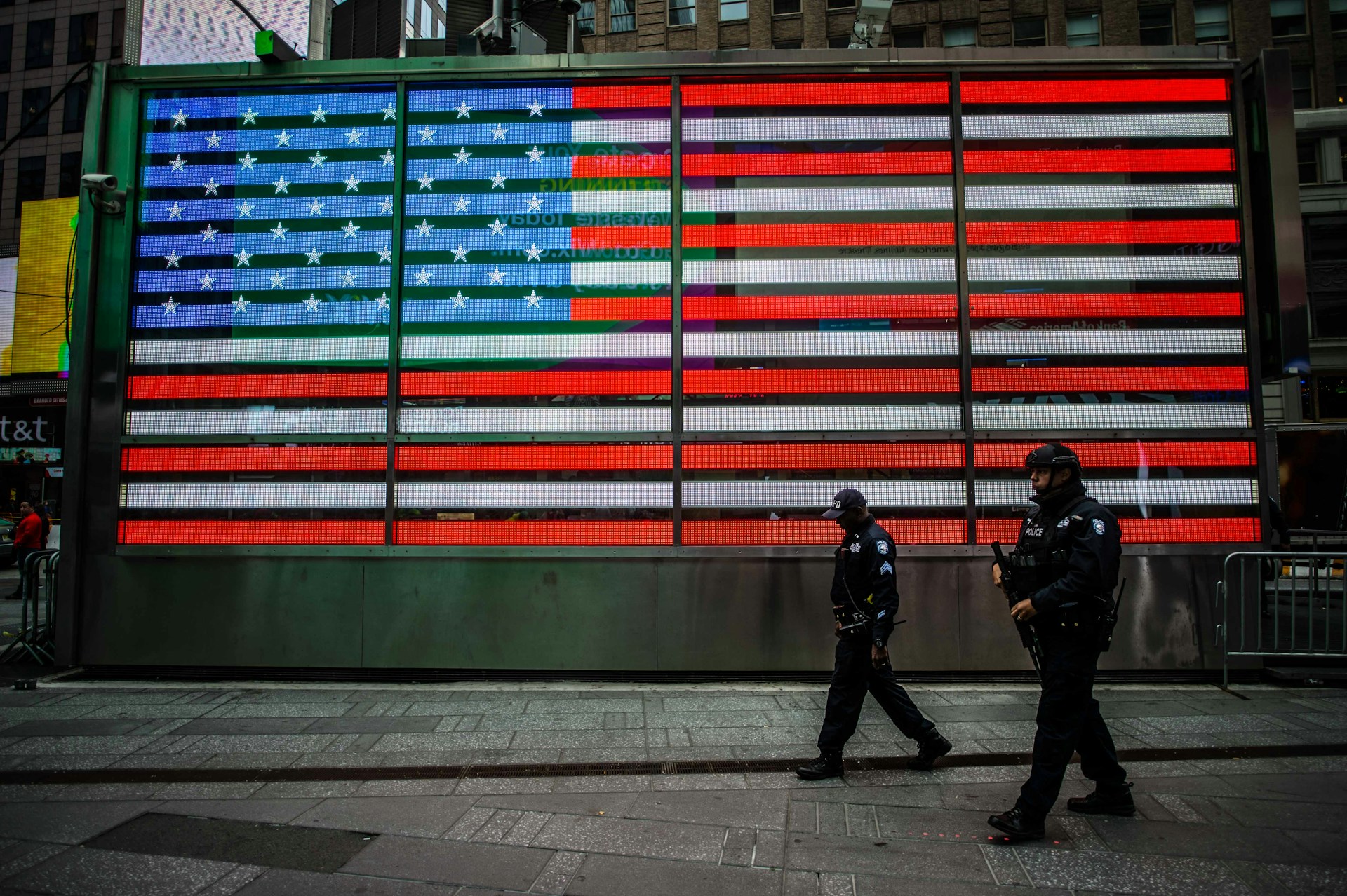 two man walks near USA flag wall