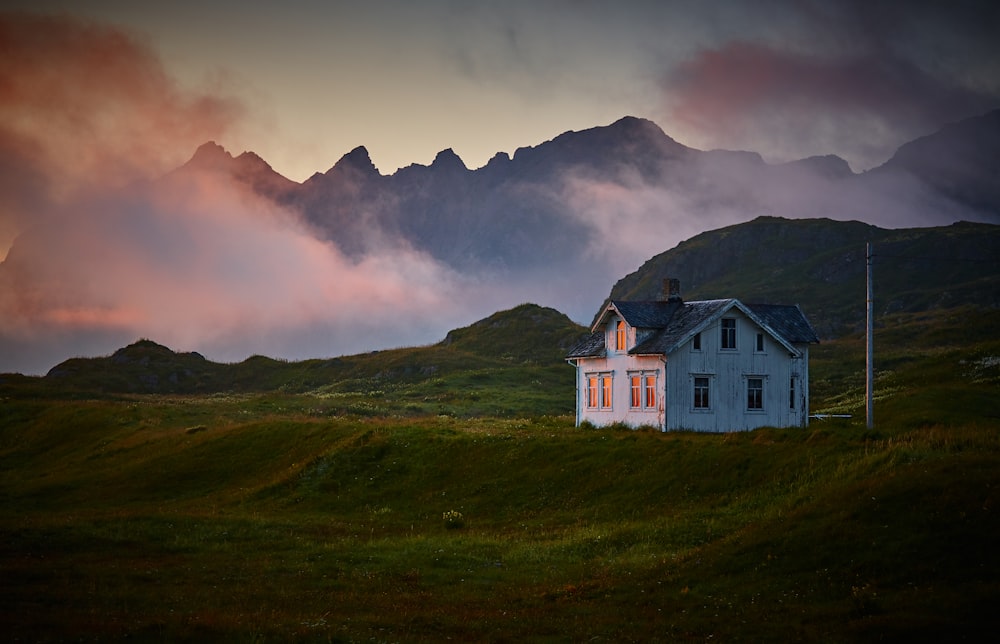 Casa blanca y gris cerca de la montaña bajo las nubes