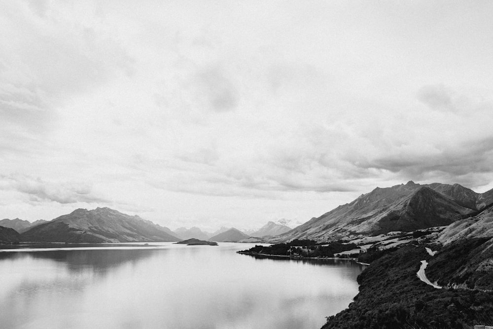 Photographie de paysage en niveaux de gris d’un lac près des montagnes