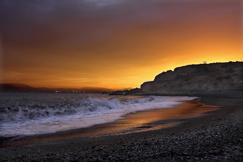 Fotografía de paisaje de la orilla del mar cerca del acantilado