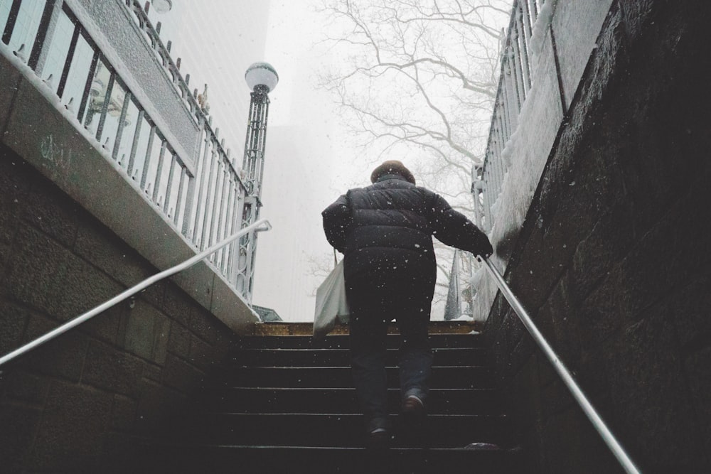 Person, die auf der Treppe geht und sich am Geländer unter bewölktem Himmel festhält