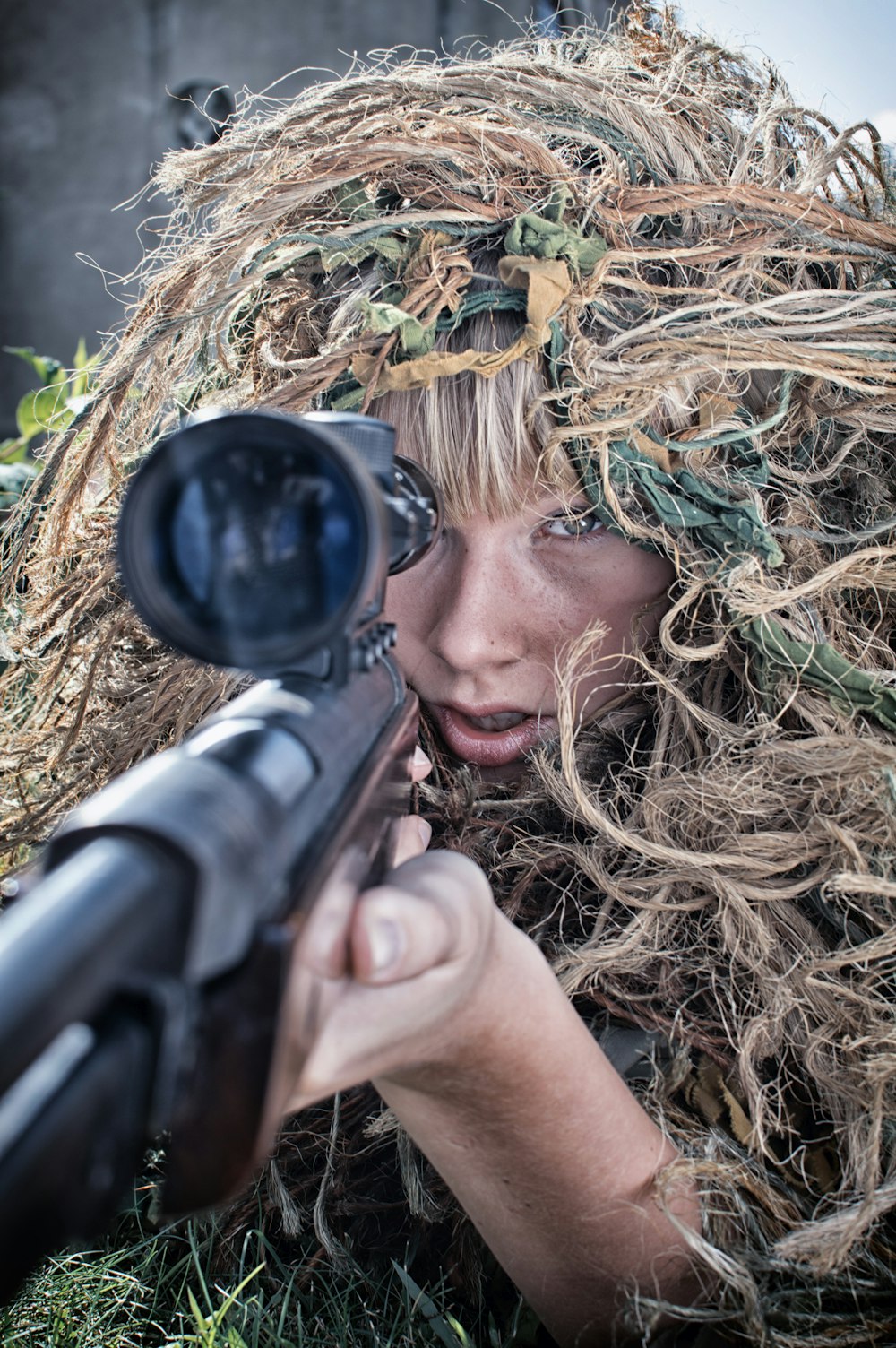 woman wearing gillie suit holding sniper rifle