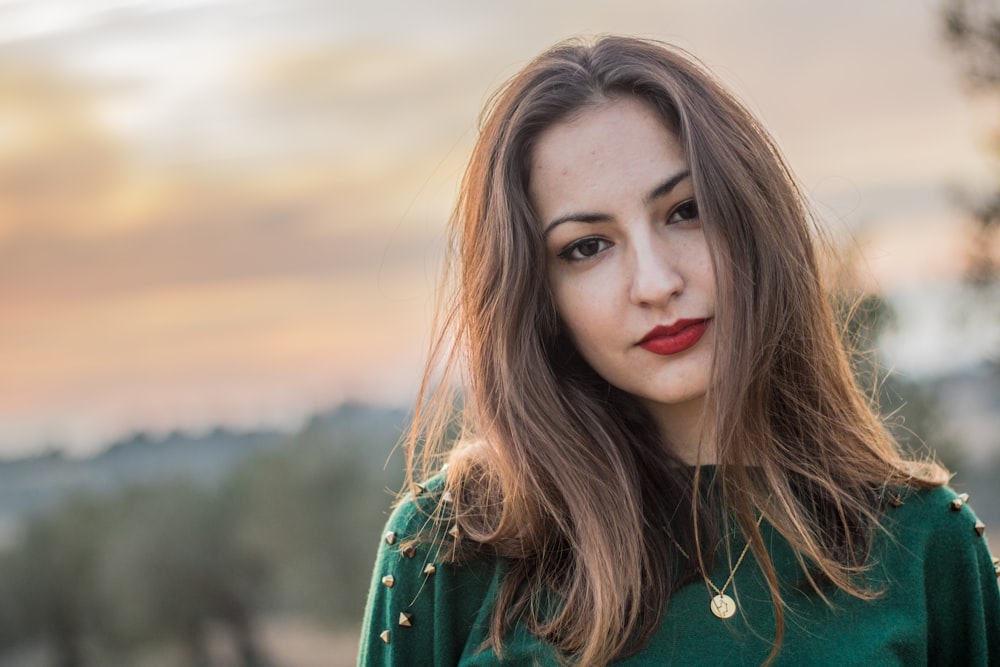 woman wearing green shirt with gold-colored pendant necklace