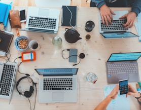 people sitting down near table with assorted laptop computers