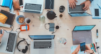 people sitting down near table with assorted laptop computers