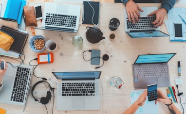 people sitting down near table with assorted laptop computers