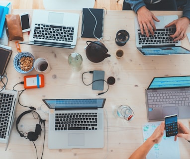 people sitting down near table with assorted laptop computers