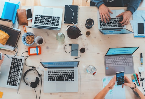 people sitting down near table with assorted laptop computers