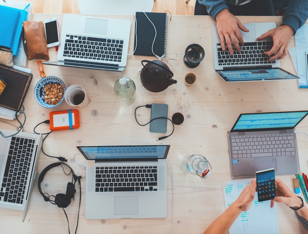 people sitting down near table with assorted laptop computers