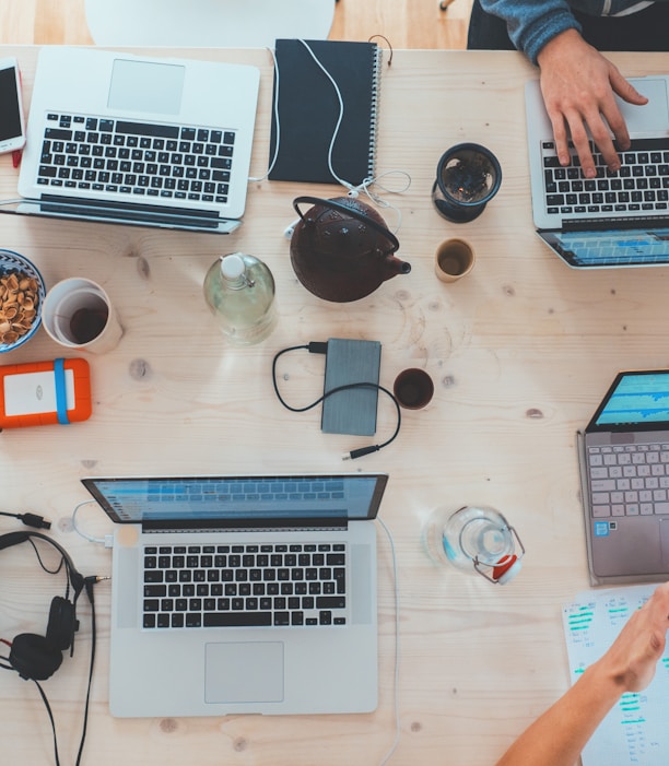 people sitting down near table with assorted laptop computers