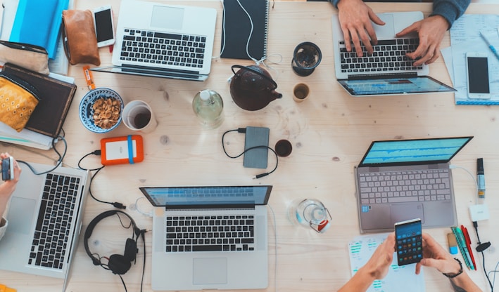 people sitting down near table with assorted laptop computers