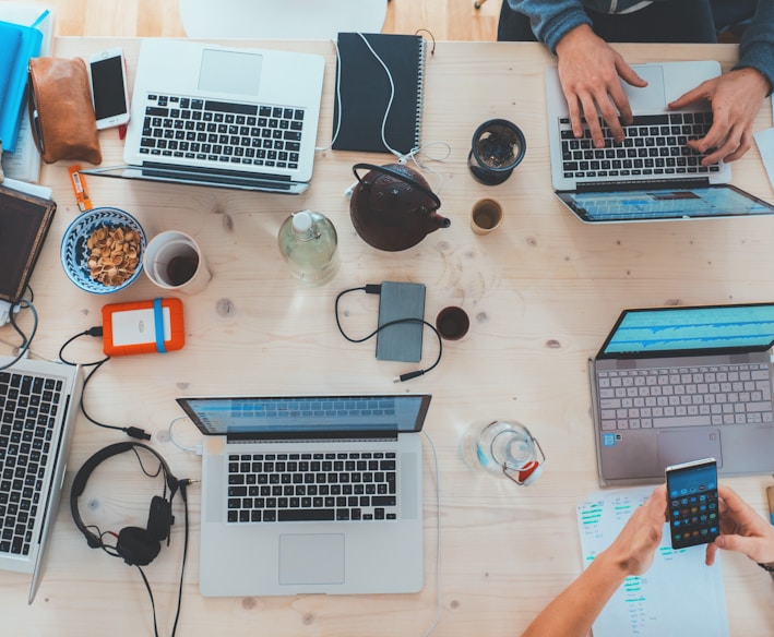 people sitting down near table with assorted laptop computers