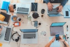 people sitting down near table with assorted laptop computers