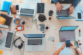 people sitting down near table with assorted laptop computers